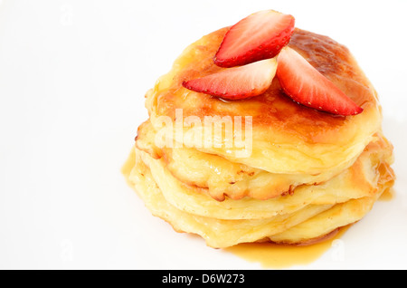 Hausgemachte Käse-Pfannkuchen mit Honig und Erdbeeren auf weißem Stockfoto