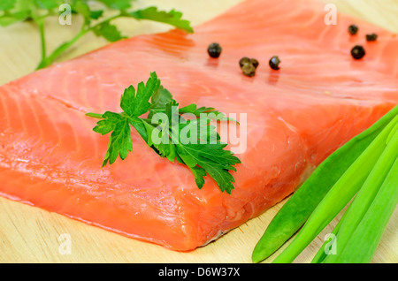 Gesalzene Lachsfilet, Petersilie und grüne Zwiebel auf ein Schneidbrett aus Holz Stockfoto