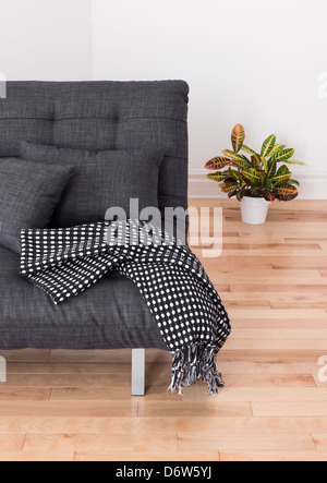 Wohnzimmer-Detail. Graue Sofa mit Kissen und werfen und bunten Pflanzen. Stockfoto