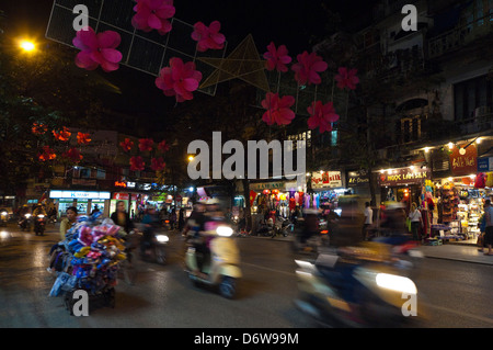 Horizontale Stadtbild Hàng Gai Straße aka Silk Street in Hanoi mit vielen Mopeds fahren entlang während der Hauptverkehrszeit in der Nacht. Stockfoto