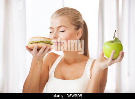 Frau, riechen, Hamburger und Holding-Apfel Stockfoto