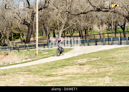 Ein älterer Mann fährt mit dem Fahrrad auf Wanderwegen durch den Norden Canadian River und Overholser See in Oklahoma City, Oklahoma, USA. Stockfoto