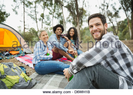 Porträt von Mitte erwachsener Mann sitzen mit Freunden beim camping