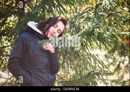 Junge Mädchen stehen in der Nähe von Fichte Zweige im sonnigen Tag Stockfoto