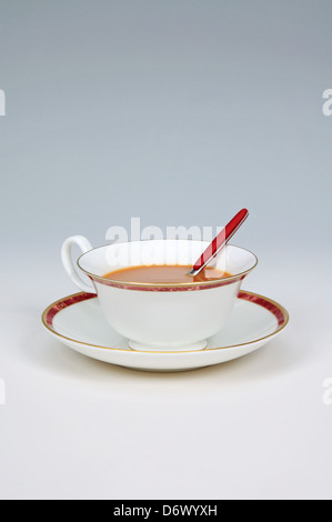 Tee mit Milch in eine weiße China Teetasse vor einem grauen Hintergrund. Stockfoto