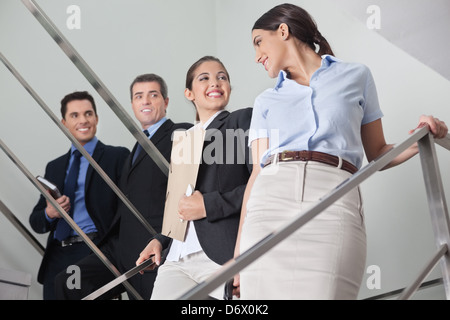 Lächelnde Geschäftsleute flirten mit zwei attraktiven Frauen im Büro Treppenhaus Stockfoto