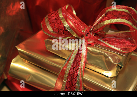 Weihnachtsgeschenke verpackt in Gold und rot mit dekorativen Bändern Stockfoto