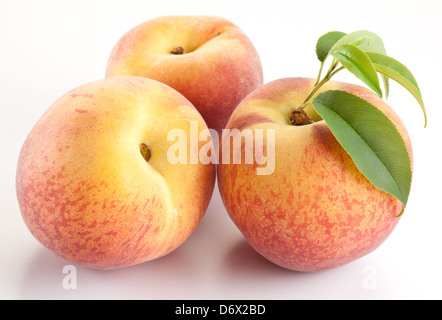Drei reifer Pfirsich mit Blättern auf weißem Hintergrund. Stockfoto