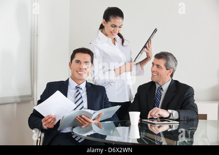 Drei glückliche Geschäftsleute arbeiten zusammen im Büro Stockfoto