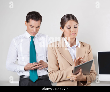 Zwei Geschäftsleute prüfen Datenaustausch zwischen Smartphone und TabletPC Stockfoto