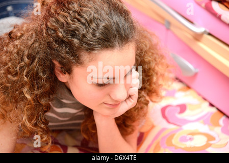 süße Mädchen mit dem lockigen Haar denken Stockfoto