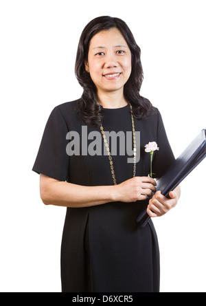 Eine vertikale Porträtfoto einer reife asiatische Frau trägt ein dunkles Kleid halten Sie einen Ordner und Blume Stockfoto