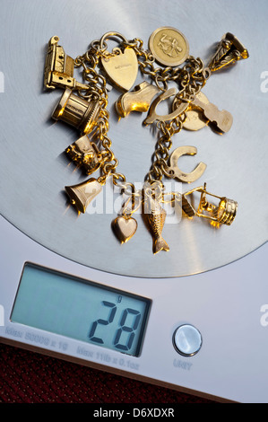GOLDSCHROTT VERKAUFEN VERKAUF GEWICHT alten Charme Armband auf Wiegemaschine Anzeige 28 Gramm Gewicht Stockfoto