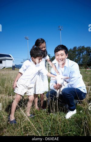 Vater und Kinder mit einer Ziege in einer farm Stockfoto