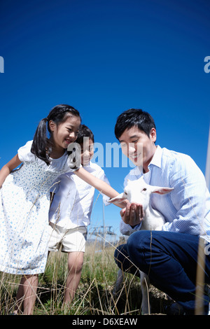 Vater und Kinder mit einer Ziege in einer farm Stockfoto