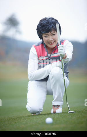 eine Frau betrachtet man einen Golfball auf dem Rasen Stockfoto