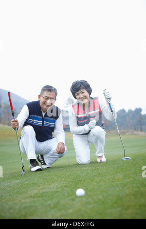 ein paar Lächeln und kniete auf einem Golfplatz Stockfoto