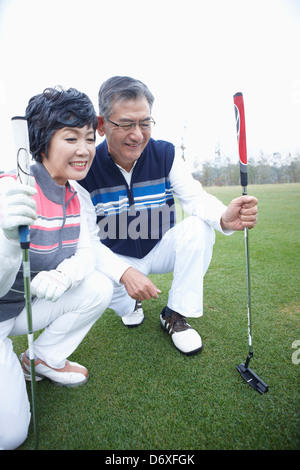 ein paar Lächeln und kniete auf einem Golfplatz Stockfoto