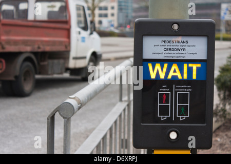 Fußgänger warten Schild am Pelican Crossing in den Sprachen Englisch und Walisisch. Stockfoto