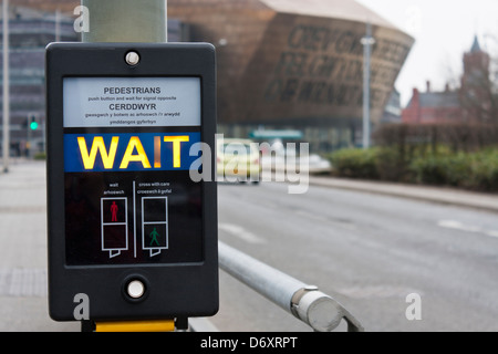 Fußgänger warten Schild am Pelican Crossing in den Sprachen Englisch und Walisisch. Wales Millennium Centre im Hintergrund. Stockfoto