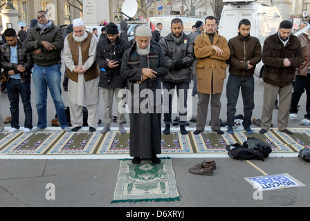 GRUPPE VON MUSLIMISCHEN MANN ZU BETEN UND DURCHFÜHRUNG NAMAZ AM TRAFALGAR SQUARE Stockfoto