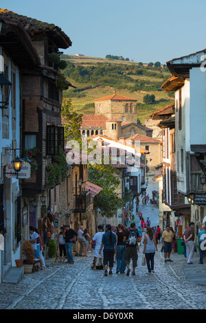 Touristen gehen vorbei an mittelalterlichen Gebäuden entlang der gepflasterten Straße Calle Del Kanton in Santillana del Mar, Kantabrien, Nordspanien Stockfoto
