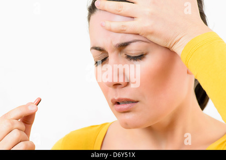 Junge Frau, die mit einer Pille Kopfschmerzen Stockfoto