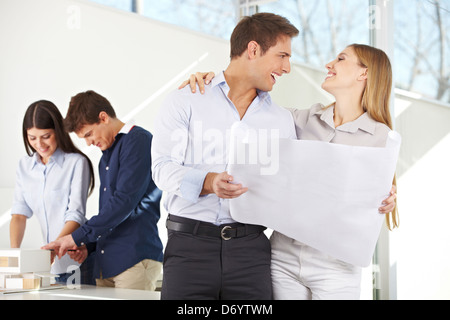 Brautpaar mit Bauplan für ihr neues Haus in Architekturbüro Stockfoto