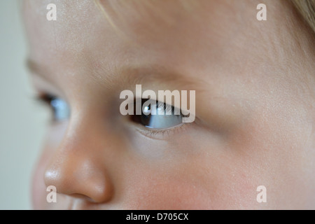 Ein Porträt eines kleinen Jungen im Alter von achtzehn Monate alt, mit braunen Haaren trägt einen blauen und weißen abgespeckten Top. Stockfoto