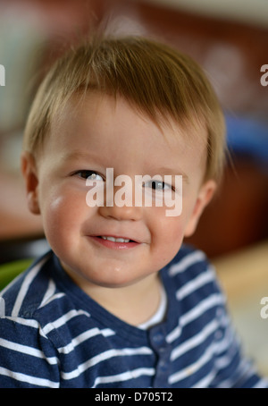 Ein Foto von lächelnden Kleinkind im Alter von achtzehn Monate alt, mit braunen Haaren tragen eine blaue und weiße abgespeckte t-Shirt. Stockfoto