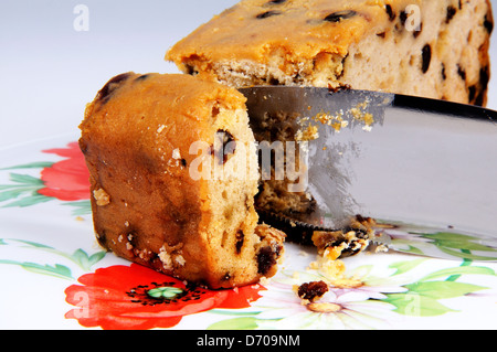 Sultana Früchtekuchen auf einem Teller mit einem Tortenmesser. Stockfoto
