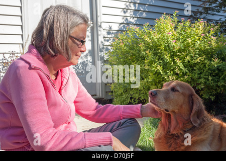 Eine Frau und ihr Hund teilen einen ruhigen Moment außerhalb. Stockfoto