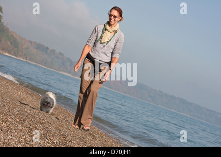 Eine Frau und ihr Hund Fuß am Lake MIchigan Strand an einem sonnigen Herbstmorgen. Stockfoto