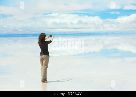 Mädchen, Bilder auf dem Handy in der Mitte des Sees Salar de Uyuni, Bolivien Stockfoto