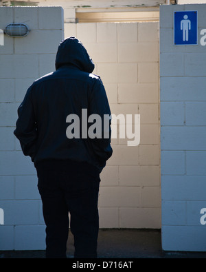 Ein Mann mit einem schwarzen Hoodie in einer öffentlichen Toilette Herren. Stockfoto