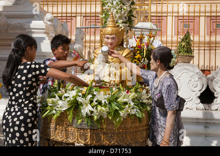 Anbeter gießt Wasser auf eine religiöse Statue an der Shwedagon-Pagode, Yangon (Rangoon), Myanmar, (Burma) Stockfoto