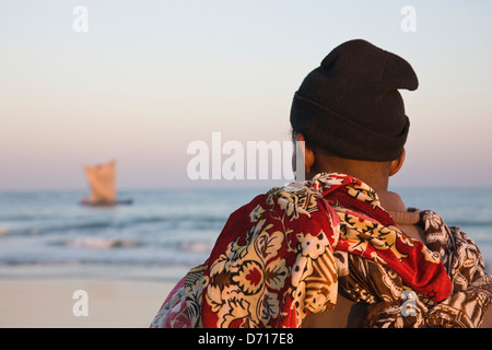 Frau beobachten Segelboot am Strand, Morondava, Madagaskar Stockfoto