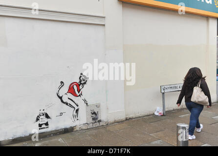 Wood Green, London, UK. 26. April 2013. Neue Graffiti an der Wand "gestohlen Banksy" außerhalb Poundland in Wood Green. Eine Frau geht vorbei an der neuen Graffiti, ein Panda mit dem Slogan "Das ist kein Banksy" und eine Katze Frau, die an der Wand des Poundland in Wood Green gemalt worden sein. Stockfoto