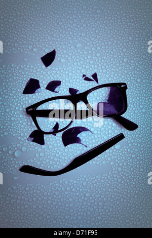 zerbrochene Sonnenbrille auf einem nassen Tisch Stockfoto
