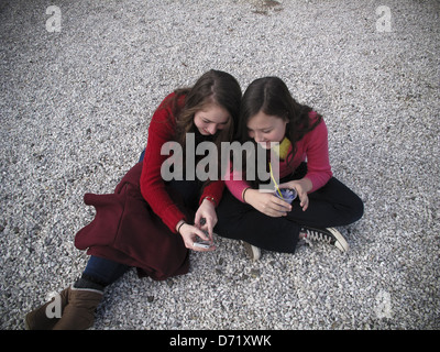 Zwei Mädchen sitzen auf Boden mit iPhone und Getränk Stockfoto