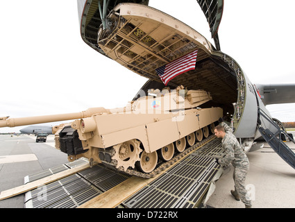 Die Flieger laden den M1 Abrams Main Battle Tank in ein C-5M Super Galaxy Frachtflugzeug, ein wichtiger Teil der Lufttransportkapazitäten der US Air Force. Diese Operation zeigt die Fähigkeit des Militärs, schwere Ausrüstung über weite Entfernungen zu transportieren. Stockfoto