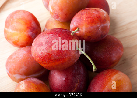 Frische feuchte Pflaumen auf Holzplatte Stockfoto