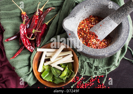 Kaffir Limetten Blätter, Zitronengras, rosa Pfefferkörner und einem Mörser und Stößel mit Crusthed Pfeffer. Stockfoto