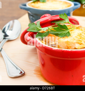 Französische Zwiebel Suppe Gratin in roten und blauen Töpfen auf Tischplatte Stockfoto