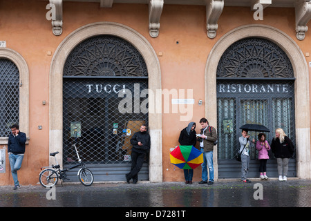 Menschen, die Zuflucht vor dem Regen unter günstigen Sonnenschirmen auf der Piazza Navona, Rom, Italien Stockfoto