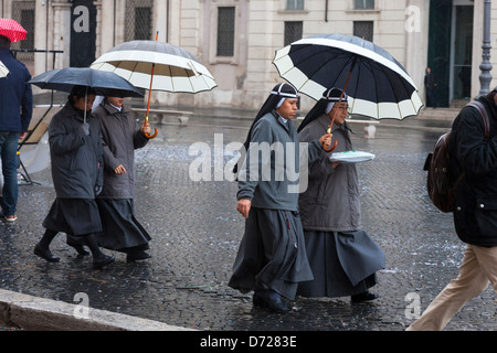 Nonnen in Eile, bergende unter Sonnenschirmen auf der Piazza Navona, Rom, Italien Stockfoto