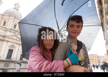 Leon und Maria Zuflucht vor dem Regen unter ein günstiges Dach auf der Piazza Navona, Rom, Italien Stockfoto