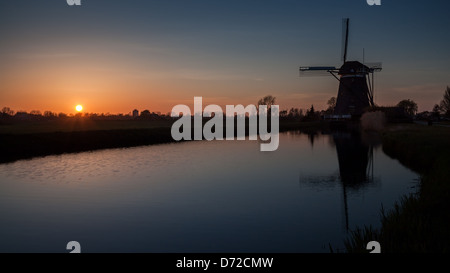 Niederländische Sonnenuntergang mit einer Windmühle spiegelt sich in einem Kanal Stockfoto