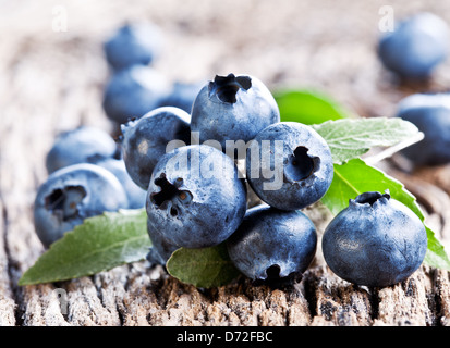 Heidelbeeren mit Blättern auf einem alten Holztisch. Stockfoto