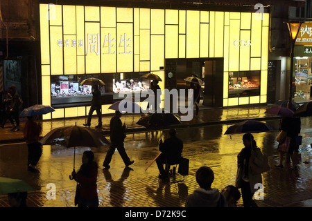 Hong Kong, China, Menschen in der Nacht im Regen draußen ein Juwelier Geschäft CSS Stockfoto